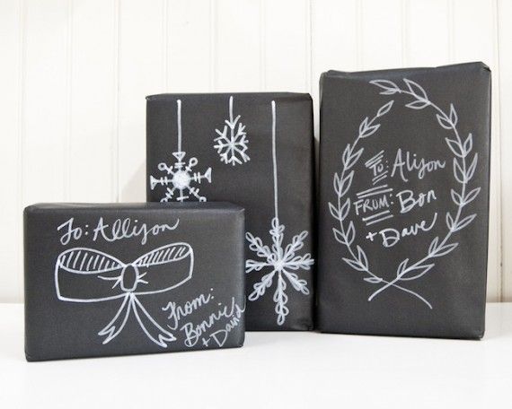 Pacchetti di Natale con carta nera e disegni bianchi in gessetto
